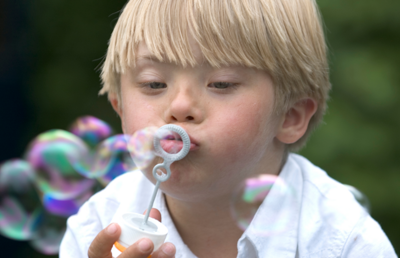 Bub mit Downsyndrom bläst Seifenblasen