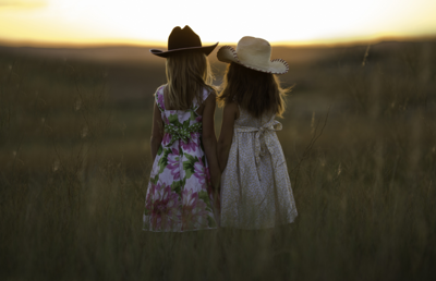 zwei Mädchen stehen auf einer Wiese und schauen in Richtung des Horizonts